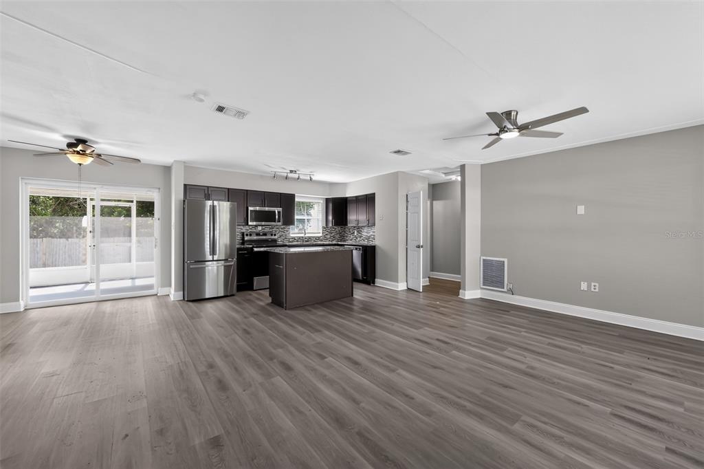 An open-concept kitchen and living area featuring dark cabinetry, a center island, and wood-look flooring — 5235 ROBIN LANE N, ST PETERSBURG, FL