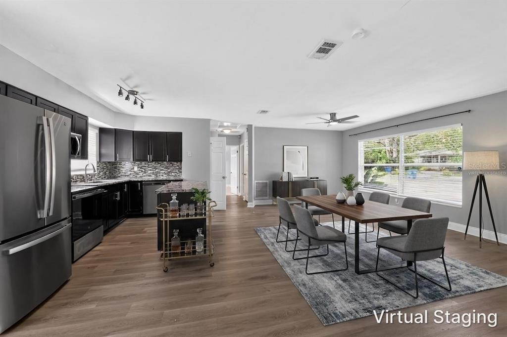 A kitchen and dining area with dark cabinets, stainless steel appliances, and wood-look flooring — 5235 ROBIN LANE N, ST PETERSBURG, FL