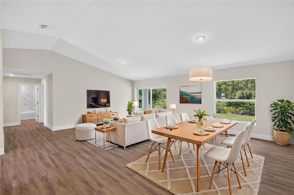 A bright, open-concept living and dining area features wood-look flooring, neutral walls, and large windows — 151 KIRBY STREET, PORT CHARLOTTE, FL
