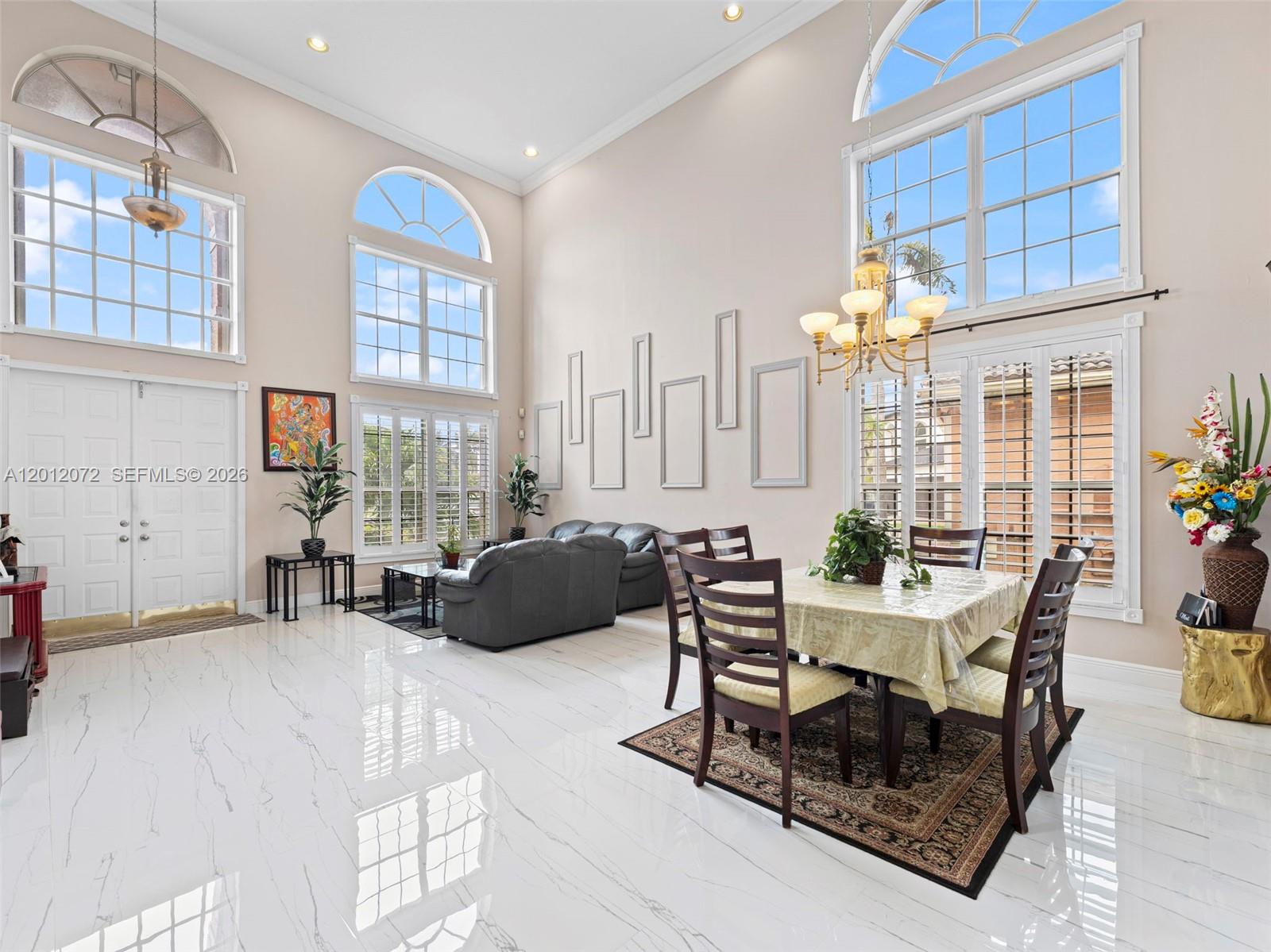 A high-ceilinged living and dining room features white marble floors and large arched windows — 16455 SW 20th St, Miramar FL 33027, MIRAMAR, FL