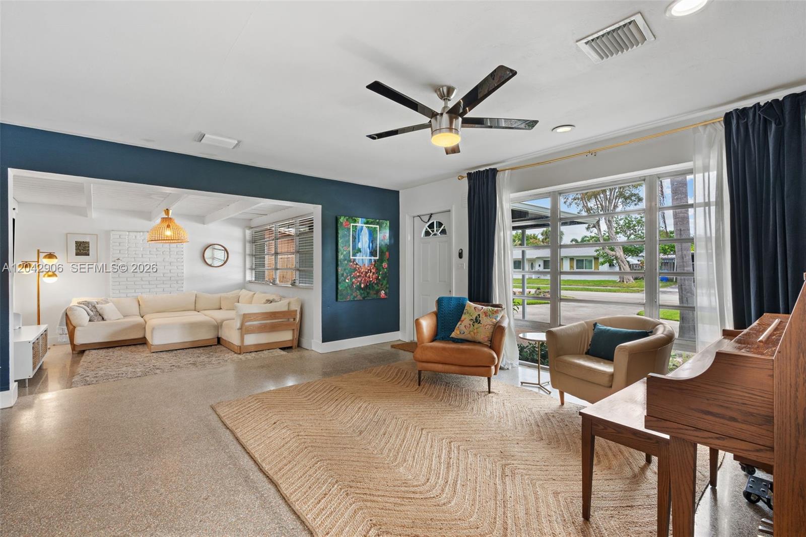 A living room features a blue accent wall, a large rug, and a seating area — 1250 NE 23rd Pl, Pompano Beach FL 33064, POMPANO BEACH, FL