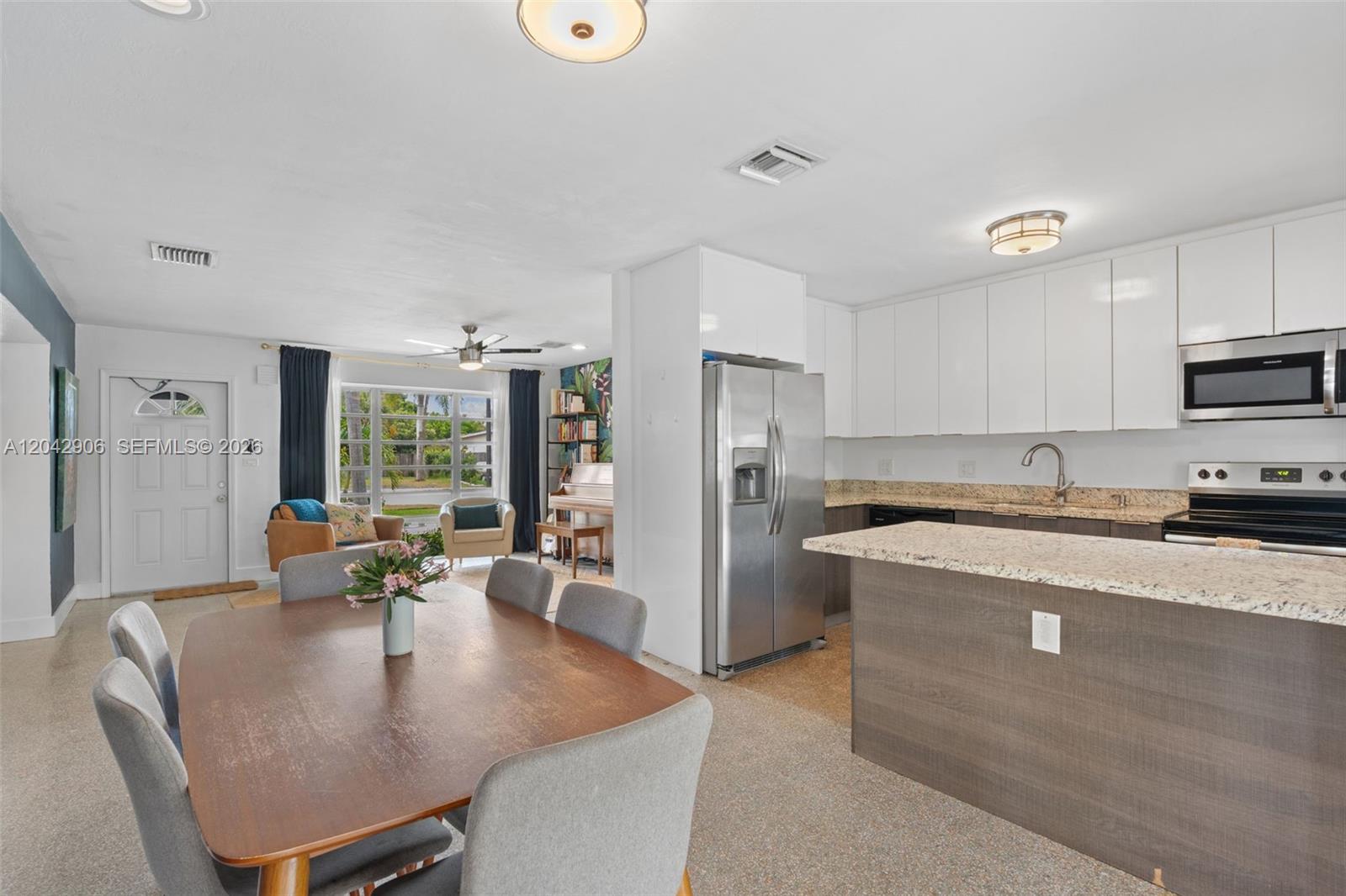A dining area opens into a kitchen with stainless steel appliances and granite countertops — 1250 NE 23rd Pl, Pompano Beach FL 33064, POMPANO BEACH, FL