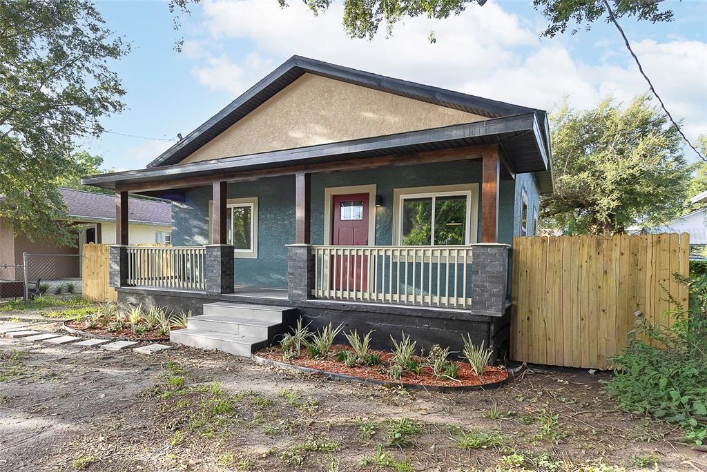 A blue house with a front porch, red door, and wooden fence under a sky — 3203 E EMMA STREET, TAMPA, FL