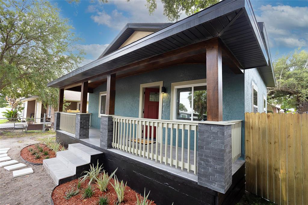 A teal house with a covered front porch, dark wood columns, and stone pillar bases — 3203 E EMMA STREET, TAMPA, FL