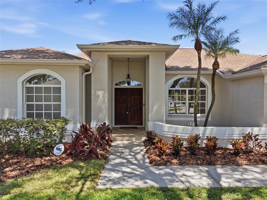 The exterior of a single-story house features a double front door and arched windows — 859 INVERRY DRIVE, OLDSMAR, FL