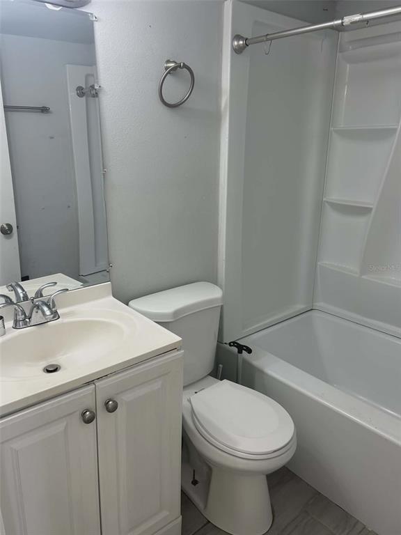 A bathroom features a white vanity with a sink, a toilet, and a shower-tub combo — 1106 50TH AVENUE DRIVE W, BRADENTON, FL