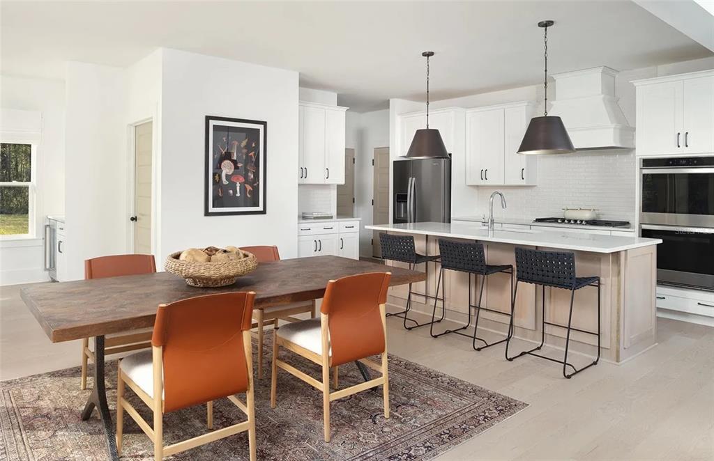 A kitchen and dining area with white cabinets, a large island, and a wooden table — 2672 VERONA LANE, ODESSA, FL
