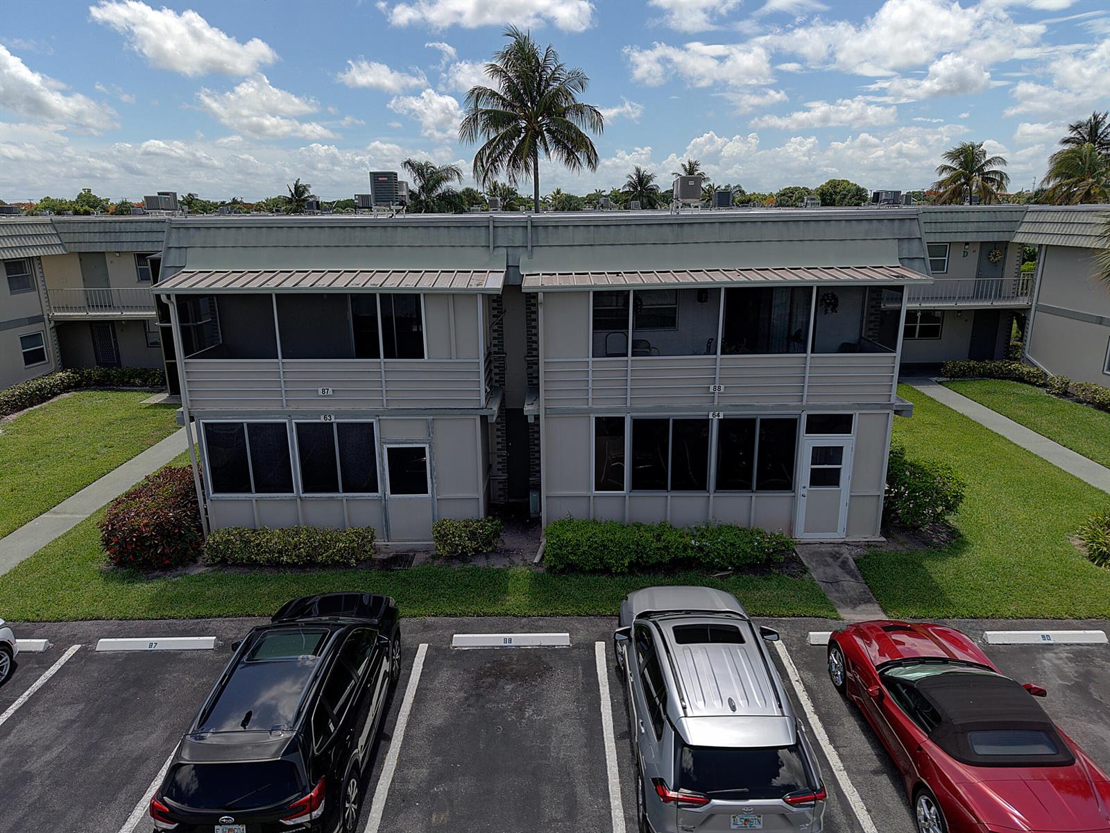 An exterior view of a two-story apartment building with a parking lot in front — 87 Brittany B Avenue # B, Delray Beach FL 33446, DELRAY BEACH, FL