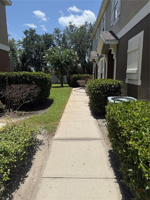 A concrete sidewalk leads between two residential buildings flanked by green hedges and trees — 1993 ESTANCIA CIRCLE UNIT B, KISSIMMEE, FL