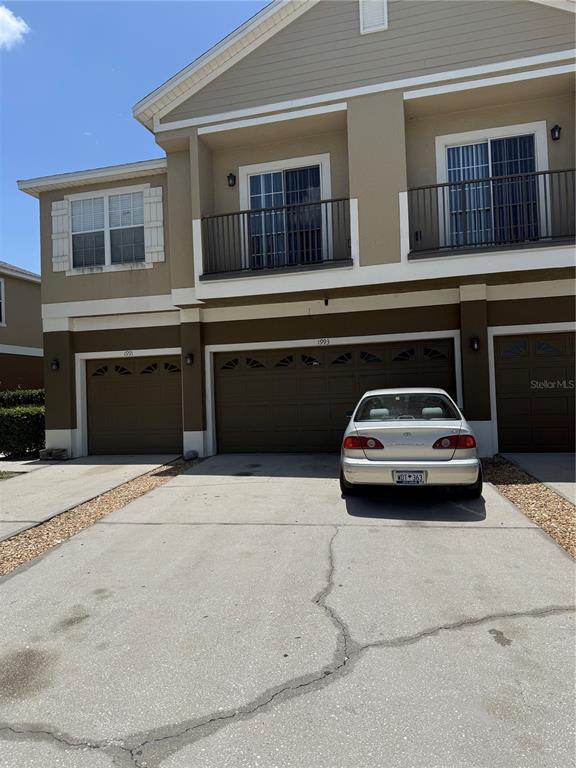 A two-story townhouse exterior features a beige facade, brown garage doors, and two upper balconies — 1993 ESTANCIA CIRCLE UNIT B, KISSIMMEE, FL