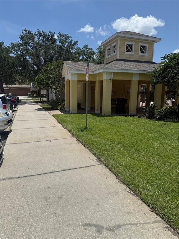 A sidewalk leads to a yellow community building with a tower and covered patio area — 1993 ESTANCIA CIRCLE UNIT B, KISSIMMEE, FL