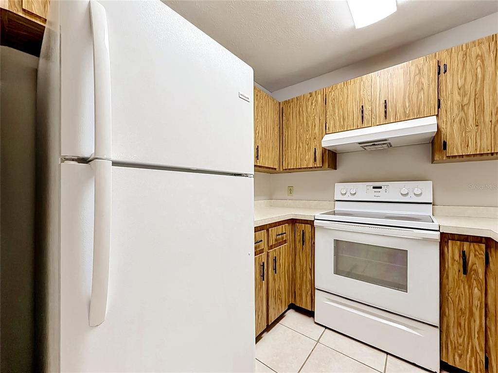 A kitchen features white appliances, wood-grain cabinets, and light-colored tile flooring — 2113 NE 38TH AVENUE, OCALA, FL