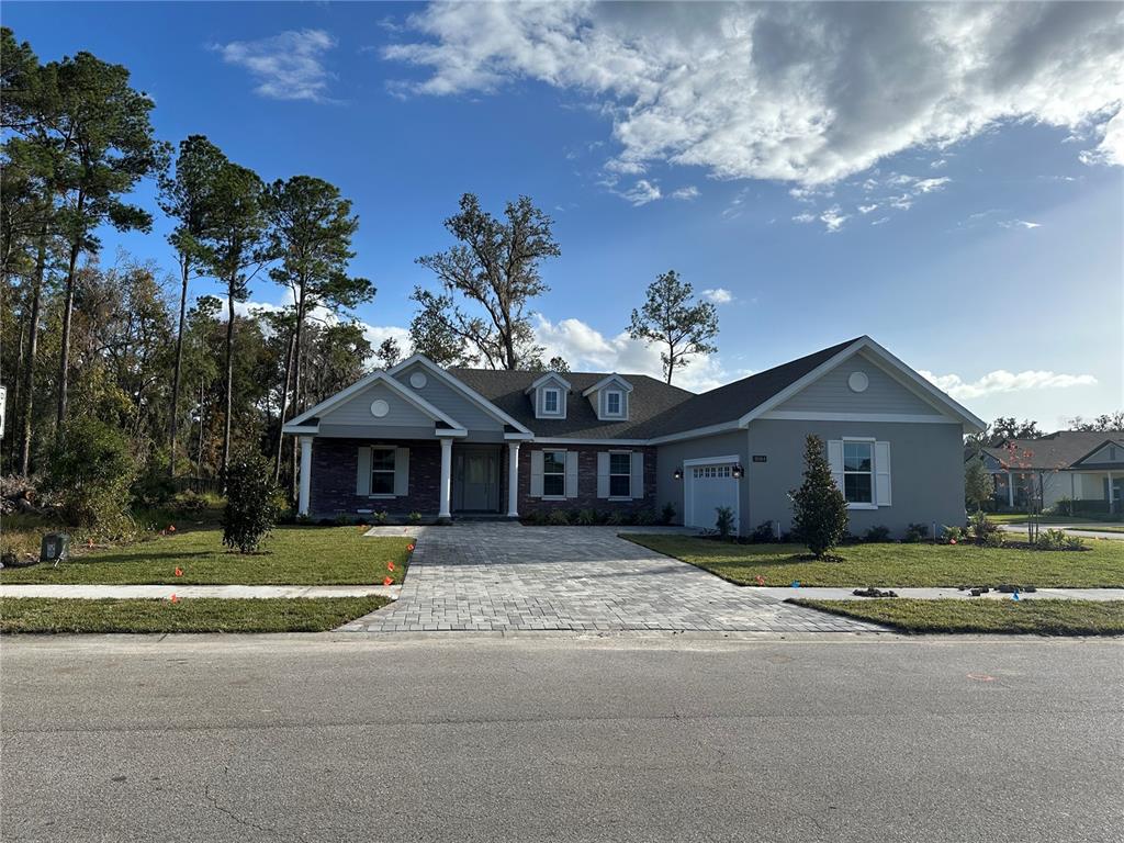 A single-story house with a stone facade, gray siding, and a paved driveway — 19364 SHELTERED HILL DRIVE, BROOKSVILLE, FL