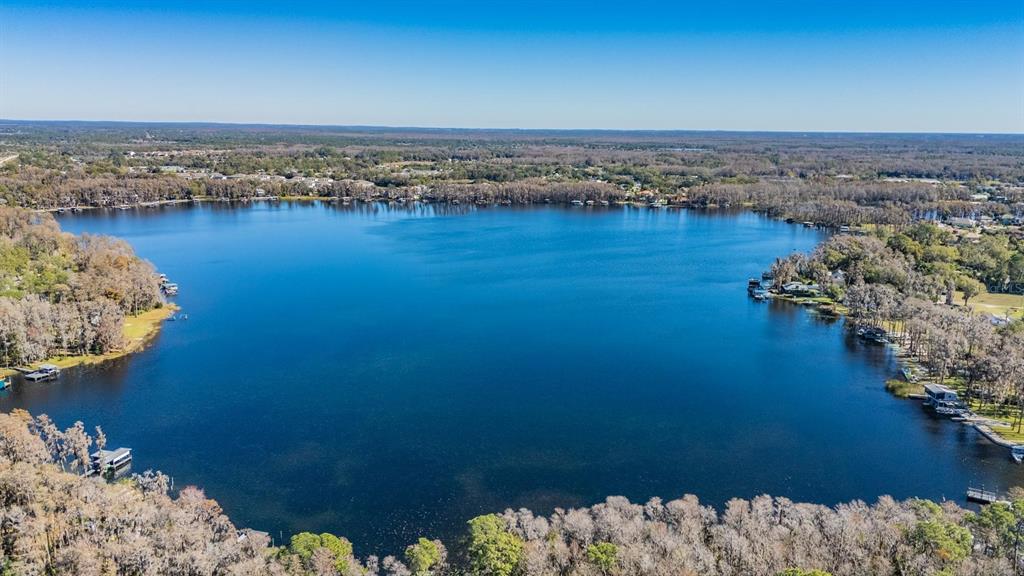 An aerial view of a large lake surrounded by trees and residential properties — 5504 SUN UP ROAD, LAND O LAKES, FL