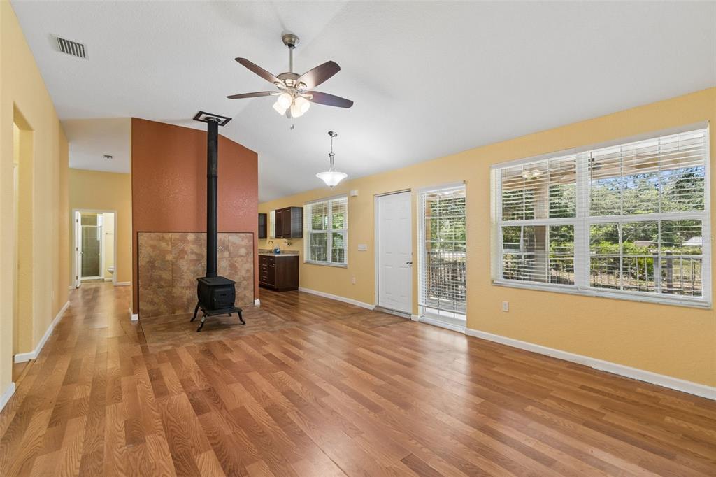 A living room with wood flooring, a wood-burning stove, and a vaulted ceiling — 11274 S RIVIERA DRIVE, HOMOSASSA, FL