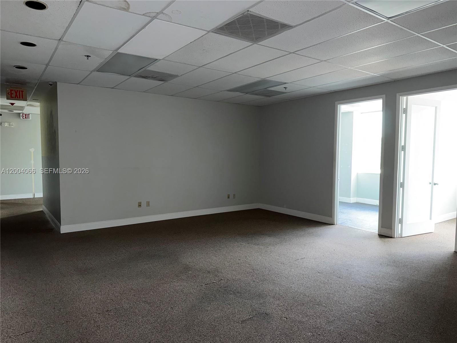 An empty office room features gray walls, brown carpeting, and a drop ceiling with recessed lighting — 4400 W Sample Rd # 230, Coconut Creek FL 33073, COCONUT CREEK, FL