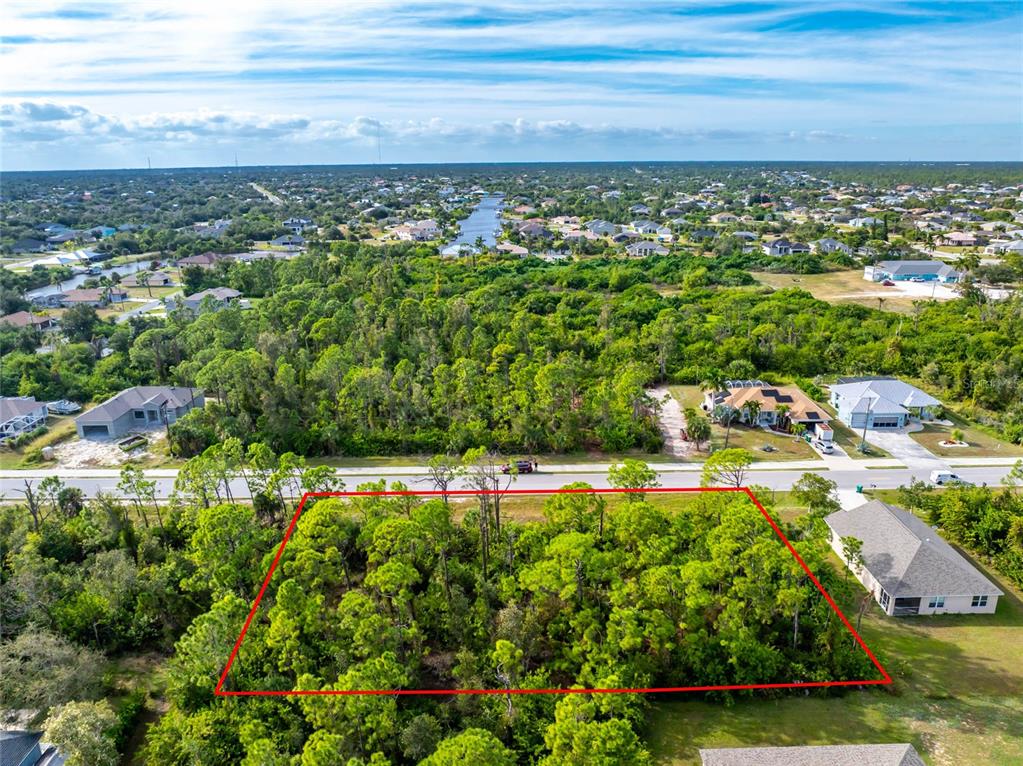 An aerial view shows a rectangular, tree-covered vacant lot outlined in red along a road — 9412 HALLENDALE DRIVE, PORT CHARLOTTE, FL