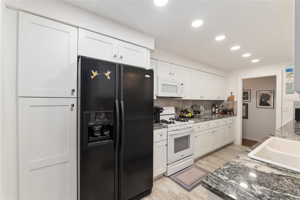 A kitchen features white cabinetry, a black refrigerator, a white stove, and dark granite countertops — 1210 SE 14TH AVENUE, OCALA, FL