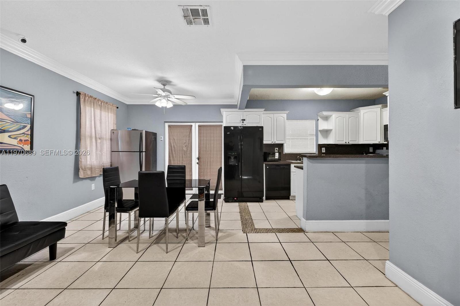 A dining area with a glass table and black chairs sits beside a kitchen — 2741 NW 43rd Ter, Miami FL 33142, MIAMI, FL