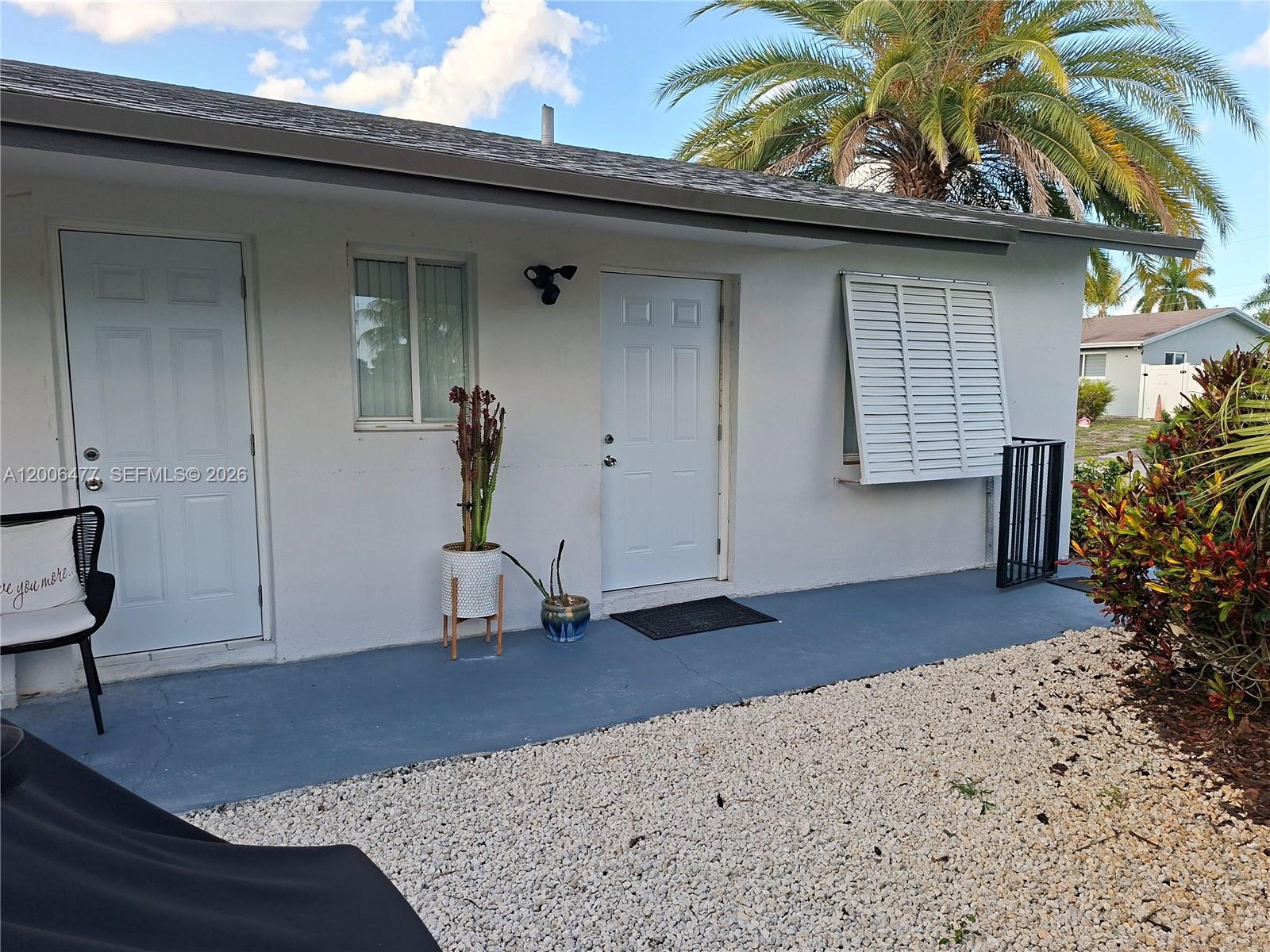The exterior of a white house features two doors, a window with shutters, and a patio — 1814 SW 97th Terrace # A, Miramar FL 33025, MIRAMAR, FL