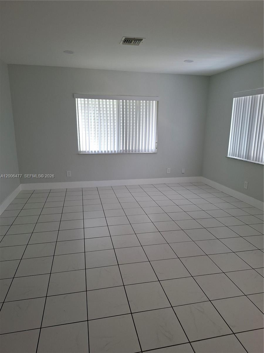 An empty room features white tiled flooring, light gray walls, and two windows with blinds — 1814 SW 97th Terrace # A, Miramar FL 33025, MIRAMAR, FL