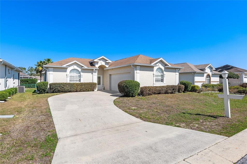 A single-story house with a beige stucco exterior, a concrete driveway, and a two-car garage — 5891 NW 26TH STREET, OCALA, FL
