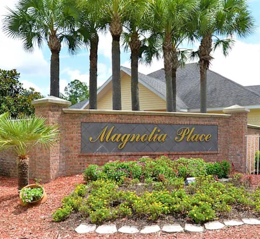 A brick monument sign for Magnolia Place stands in front of palm trees and landscaping — 4872 NW 42ND ROAD UNIT 103, GAINESVILLE, FL