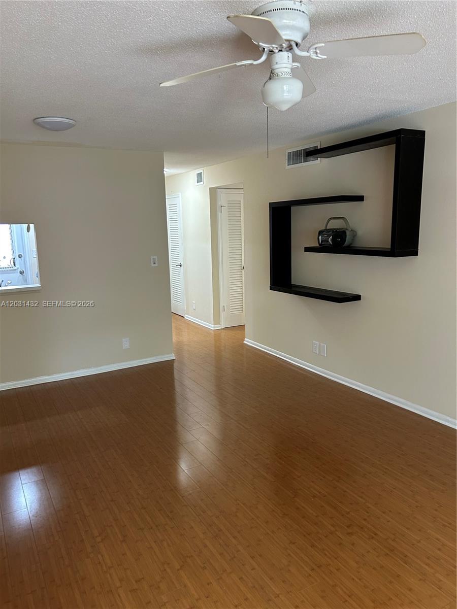 A room with wood flooring, a ceiling fan, and a black wall-mounted decorative shelf — 218 NE 12th Ave # 203, Hallandale Beach FL 33009, HALLANDALE BEACH, FL
