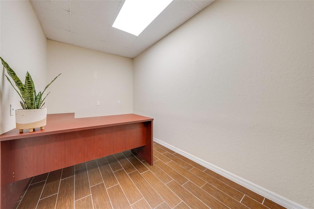 A small office with a wooden desk, a potted plant, and wood-look tile flooring — 917 EMMETT STREET, KISSIMMEE, FL