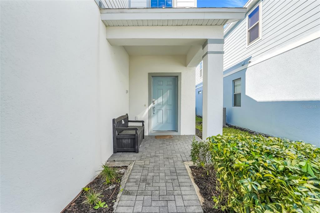 A paved walkway leads to a covered entryway with a light blue front door — 2440 TANGIER DRIVE, KISSIMMEE, FL