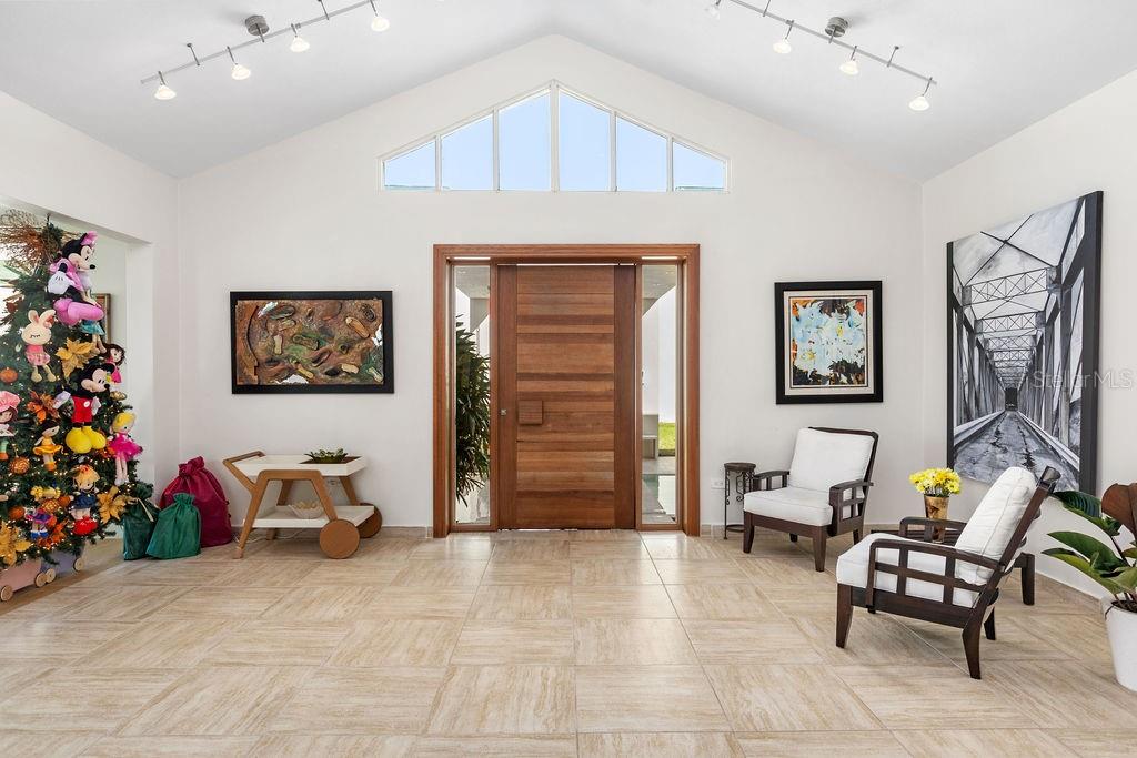 A bright, high-ceilinged entryway features tiled floors, a wooden front door, and two armchairs — 251 DORADO BEACH EAST, DORADO, PR