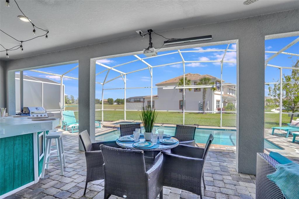 A covered patio features a dining set, a bar, and a screened-in pool area — 1533 FLANGE DRIVE, DAVENPORT, FL