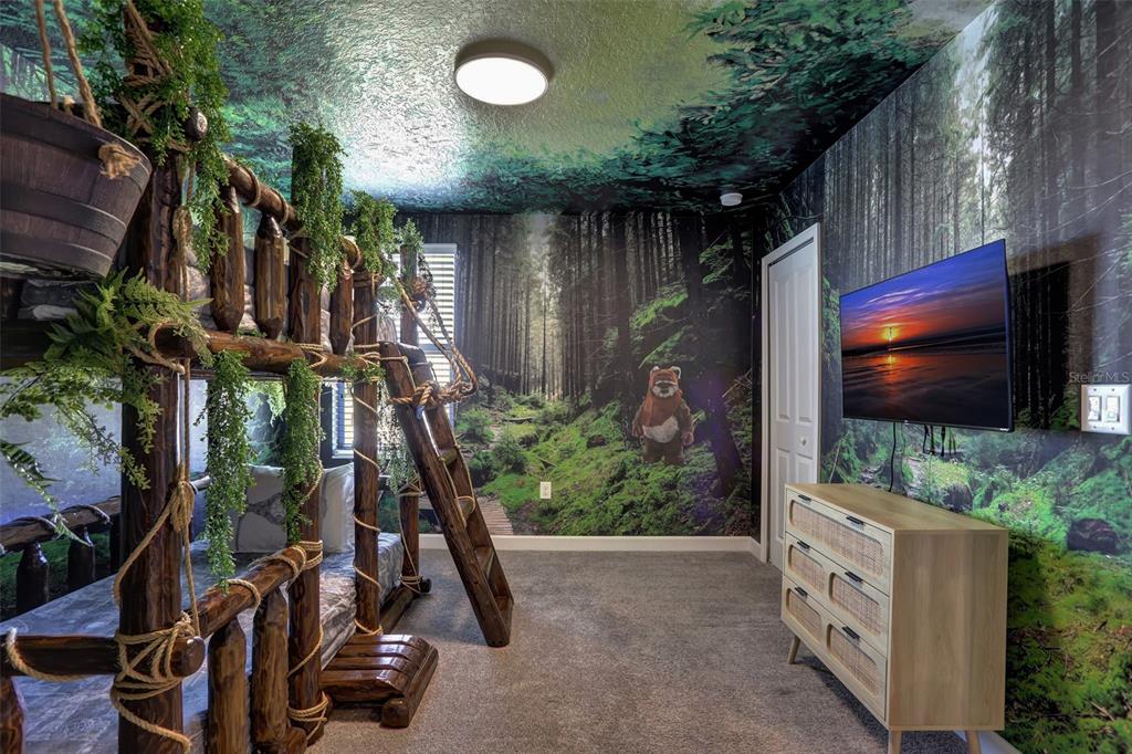 A themed bedroom features a log-style bunk bed, forest wall murals, and a television — 1533 FLANGE DRIVE, DAVENPORT, FL