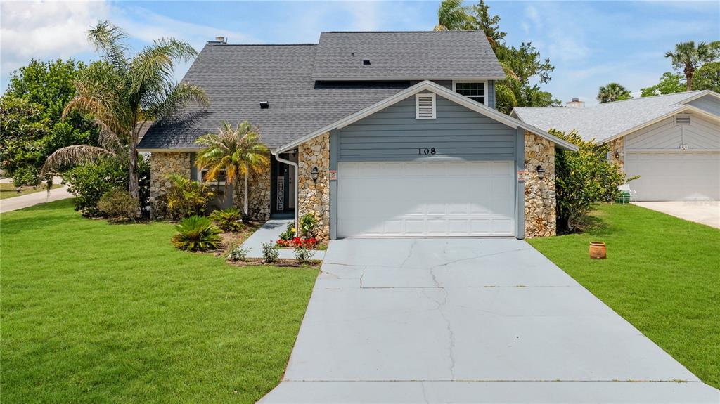 A two-story house with a stone facade, blue siding, and a two-car garage — 108 GREBE COURT, DAYTONA BEACH, FL