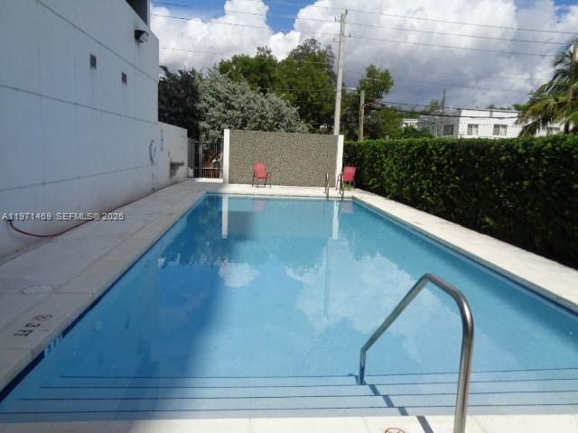 A rectangular swimming pool features a metal handrail and two red chairs on deck — 36 NW 6 Ave # 608, Miami FL 33128, MIAMI, FL