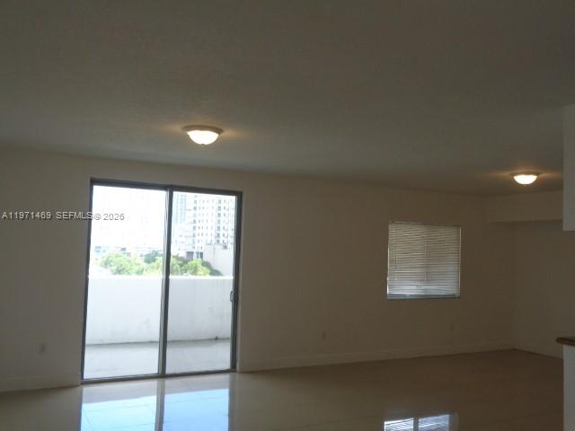 An empty living room features tile flooring, two ceiling lights, and a sliding glass balcony door — 36 NW 6 Ave # 608, Miami FL 33128, MIAMI, FL