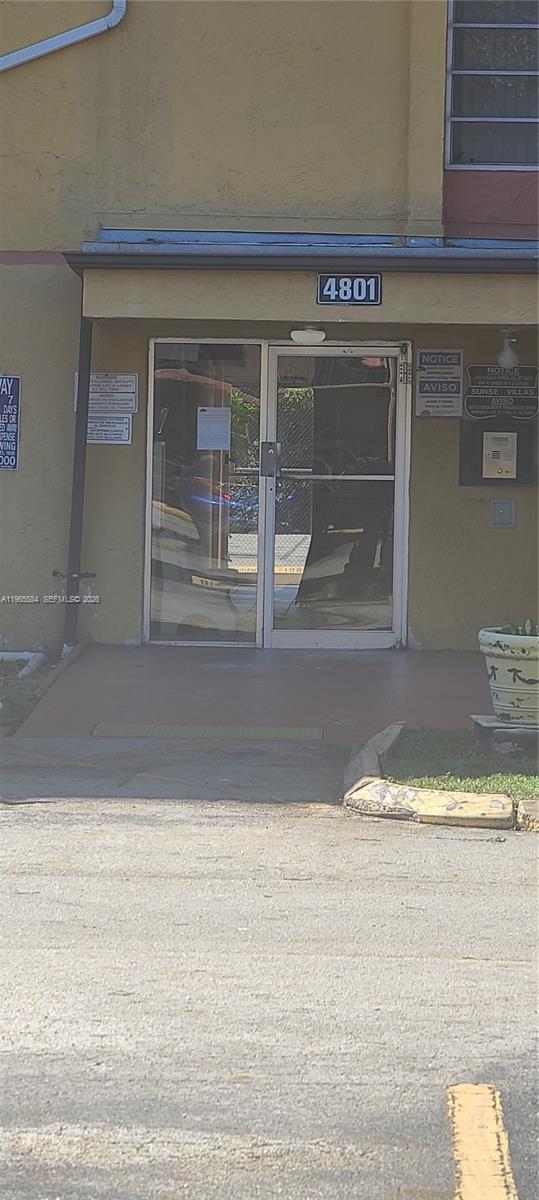 A ground-level exterior view of a building entrance with glass double doors and signage — 4801 NW 7 ST # 16, Miami FL 33126, MIAMI, FL