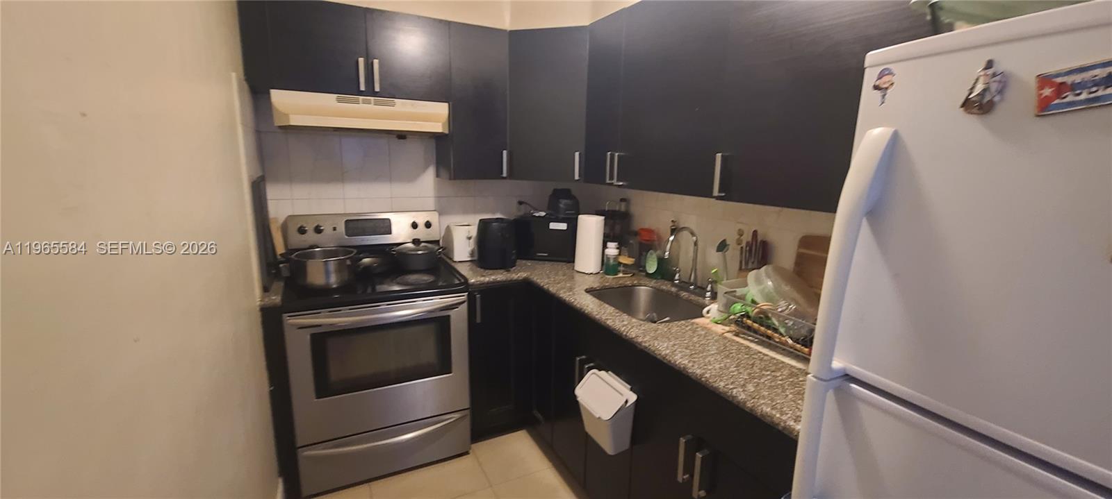 A kitchen features dark cabinets, stainless steel appliances, and granite countertops — 4801 NW 7 ST # 16, Miami FL 33126, MIAMI, FL