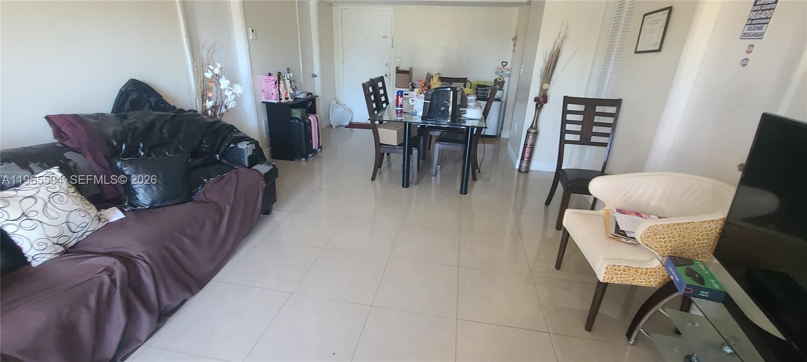 A living and dining area features tile flooring, a dark sofa, and a glass dining table — 4801 NW 7 ST # 16, Miami FL 33126, MIAMI, FL