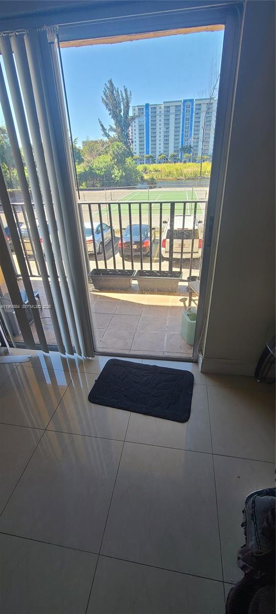 A view through a sliding glass door shows a balcony overlooking a tennis court — 4801 NW 7 ST # 16, Miami FL 33126, MIAMI, FL