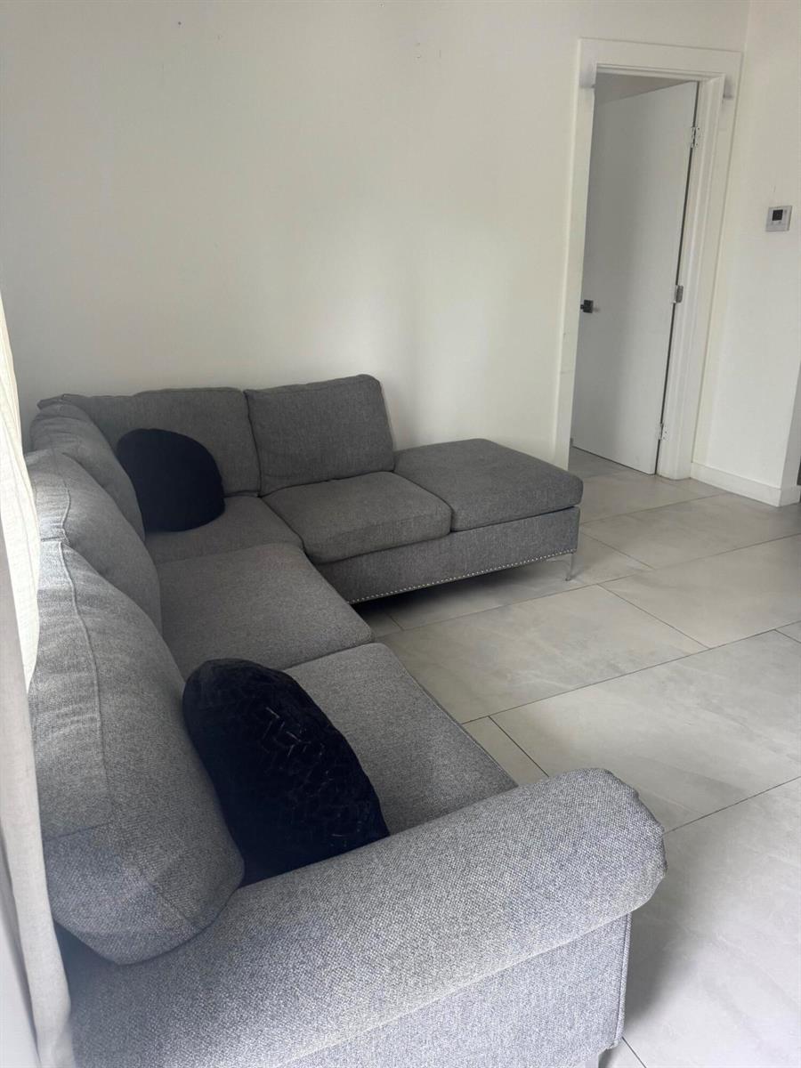 A gray sectional sofa sits on light-colored tile flooring in a living room — 2201 Greene Street # 2, Hollywood FL 33020, HOLLYWOOD, FL
