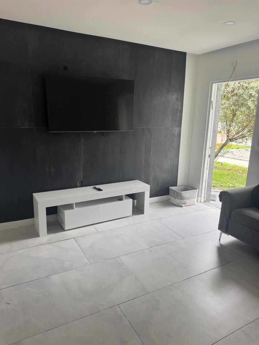 A living room features a dark accent wall with a mounted television and white console — 2201 Greene Street # 2, Hollywood FL 33020, HOLLYWOOD, FL