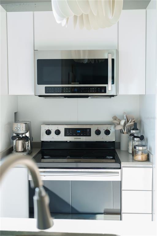 A kitchen features white cabinets, stainless steel appliances, and a glass-top electric range — 3409 ISLA VERDE AVENUE UNIT 701, CAROLINA, PR