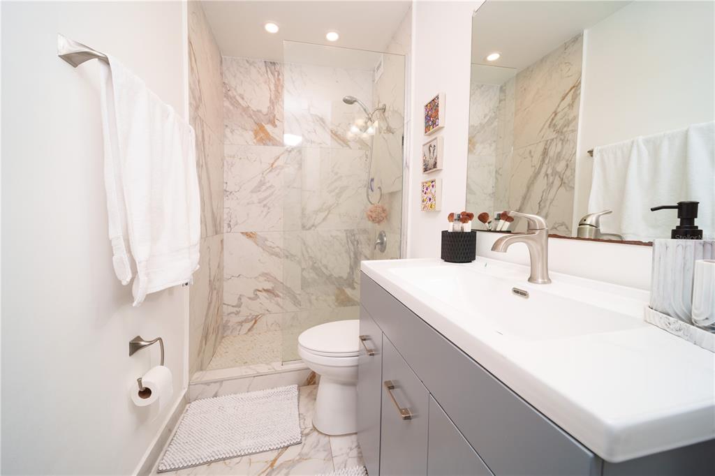 A bathroom features a gray vanity, a walk-in shower with marble tile, and a toilet — 3409 ISLA VERDE AVENUE UNIT 701, CAROLINA, PR