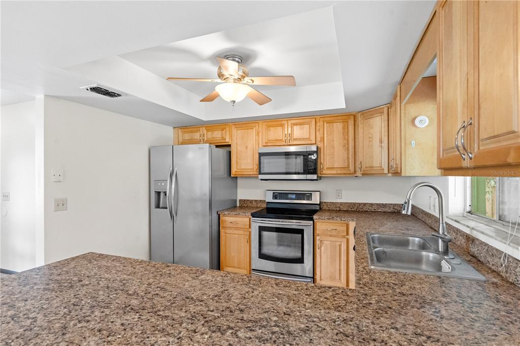 A kitchen features light wood cabinets, stainless steel appliances, and brown granite countertops — 195 GIBSON WAY, PORT ORANGE, FL