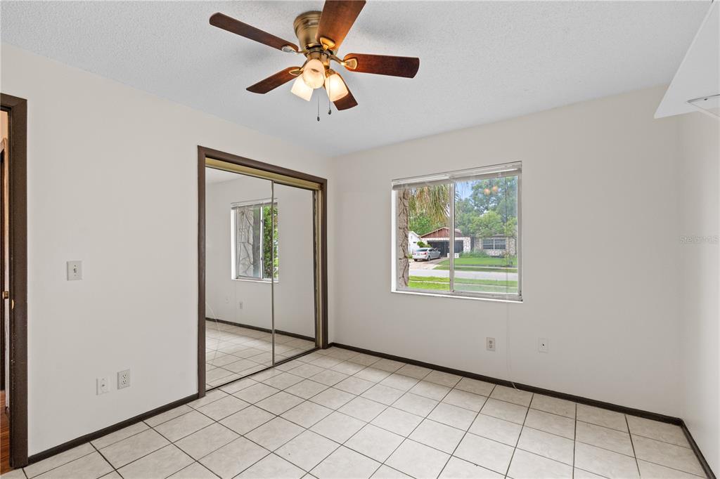 A bedroom with white walls, tile flooring, a ceiling fan, and mirrored closet doors — 195 GIBSON WAY, PORT ORANGE, FL