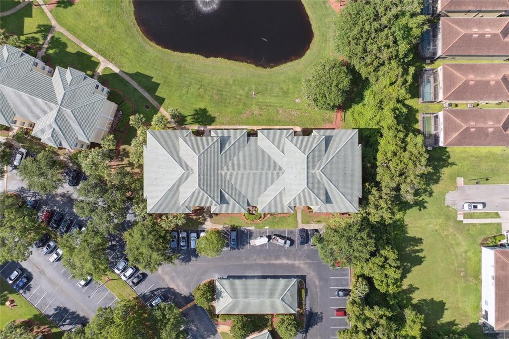 An aerial view shows a multi-unit residential building with a tiled roof and parking lot — 8816 DUNES COURT UNIT 303, KISSIMMEE, FL