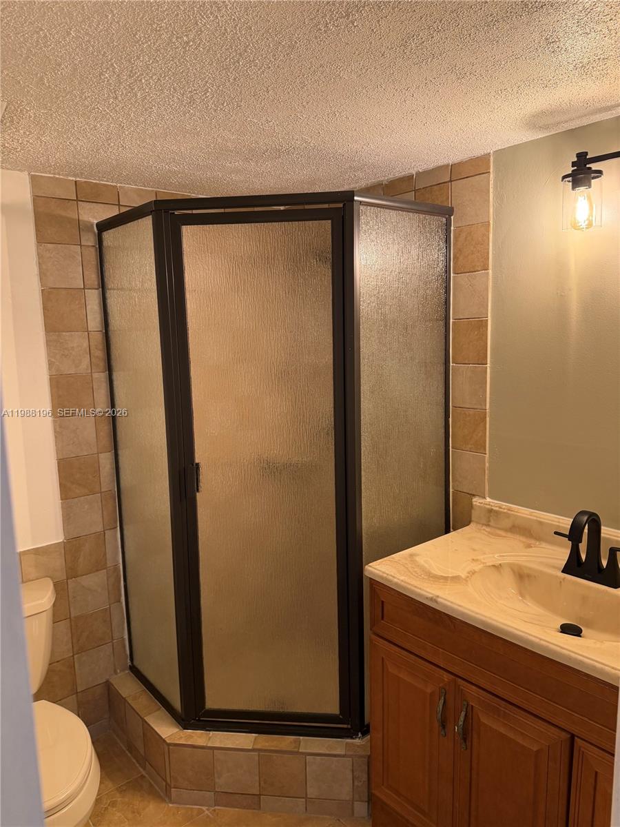 A bathroom features a corner shower with a dark frame, a vanity, and tiled walls — 9355 SW 8th St # 305, Boca Raton FL 33428, BOCA RATON, FL