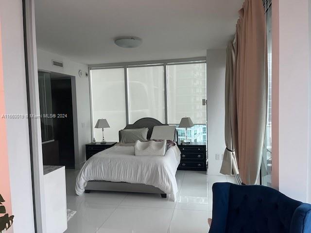 A bedroom features a bed, two nightstands with lamps, and large windows with light curtains — 1040 Biscayne Blvd # 2607, Miami FL 33132, MIAMI, FL