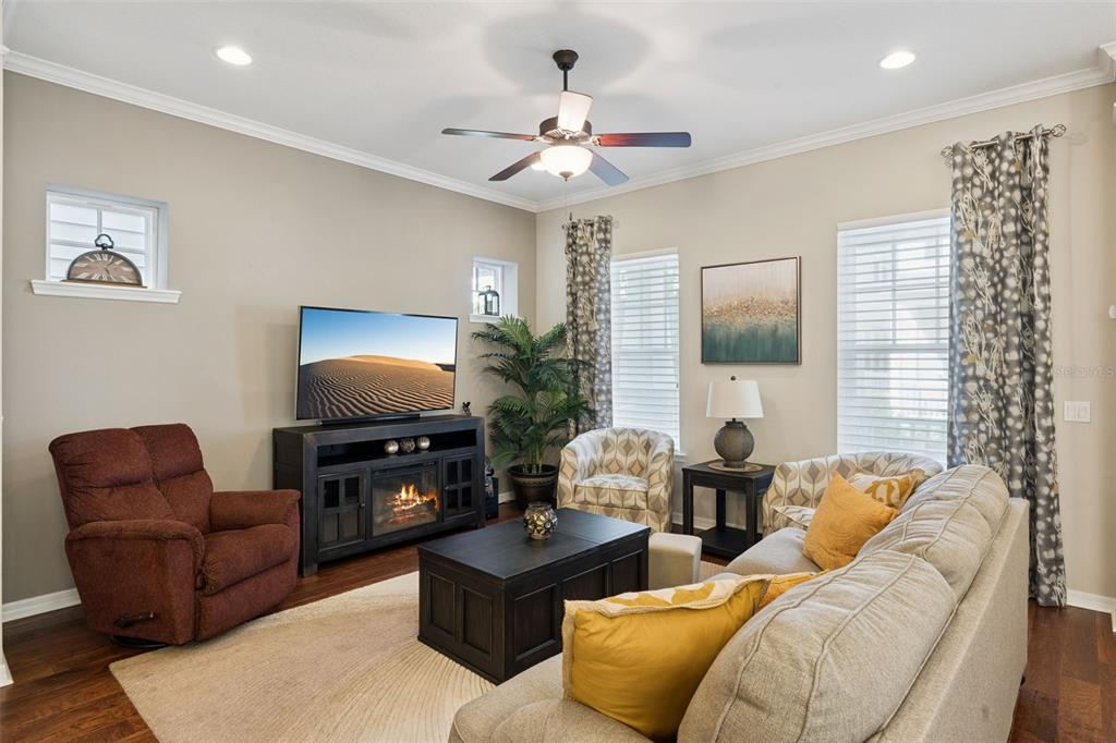A living room features a television on a fireplace console, a sofa, and an armchair — 1425 RESOLUTE STREET, CELEBRATION, FL